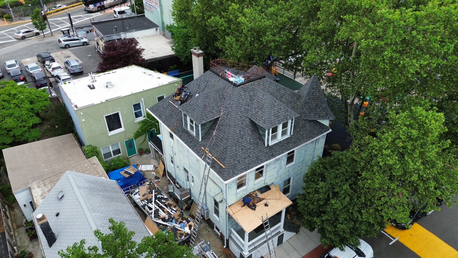 Aerial view of a Victorian home with new dark shingle roof next to a park